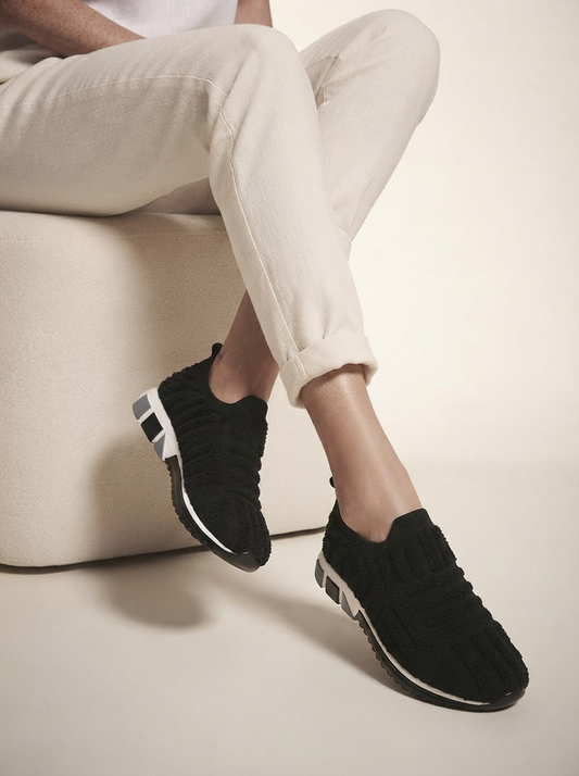 Close-up of model wearing black cushioned support sneakers