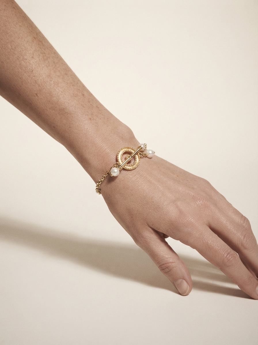Close-up of model wearing gold-tone pearl clasp bracelet